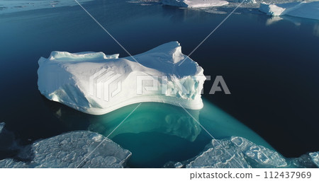 Big snow-capped iceberg in Antarctica, glacier reflected in turquoise ocean water, floating ice. Arctic winter landscape in sunny day, global warming problem. Aerial view drone flight panorama Big snow-capped iceberg in Antarctica, glacier reflected in turquoise ocean water, floating ice. Arctic winter landscape in sunny day, global warming problem. Aerial view drone flight panorama 112437969
