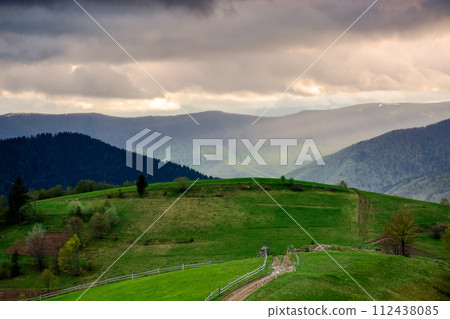 mountainous rural landscape of ukraine at sunset in spring. trees on the grassy hills rolling in to the distant valley. beautiful countryside scenery on a cloudy weather in may 112438085