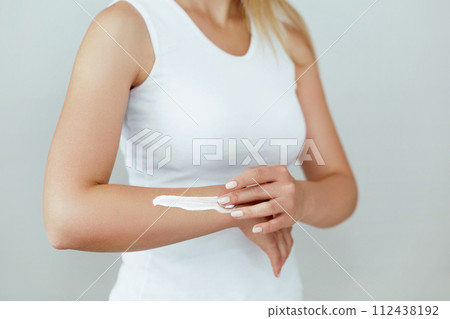 Closeup shot of woman hands holding cream and applying moisturizing hand cream. Beautiful female hands with cream. Hand Skin Care. A woman uses body lotion on your arms. Beauty And Body Care Concept Closeup shot of woman hands holding cream and applying moisturizing hand cream. Beautiful female hands with cream. Hand Skin Care. A woman uses body lotion on your arms. Beauty And Body Care Concept 112438192