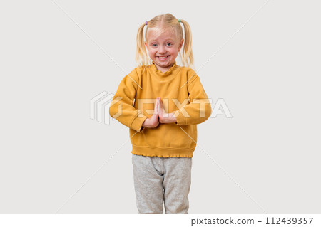 Cute little girl with blond hair in yellow sweater and gray pants is doing yoga, isolated on white background. Cute little girl with blond hair in yellow sweater and gray pants is doing yoga, isolated on white background. 112439357