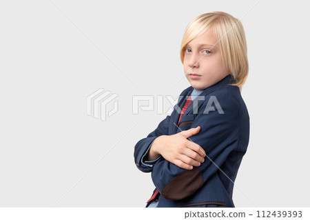 Portrait of serious schoolboy with blond hair, keeps arms crossed and looks directly at camera, isolated over white background Portrait of serious schoolboy with blond hair, keeps arms crossed and looks directly at camera, isolated over white background 112439393