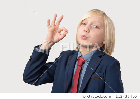 Young blond businessman shows ok sign, isolated over white background. 112439410