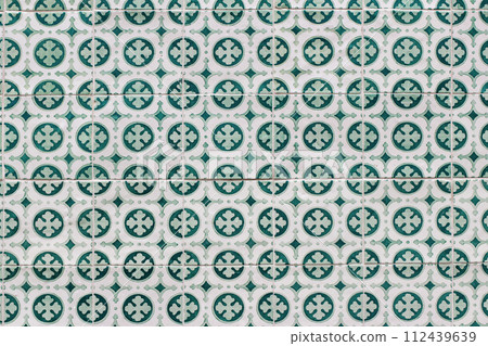 Closeup of decorative floral tiles. Traditional Portuguese ceramic tile pattern, azulejos. Clover. Irish green color. Beautiful facade, wall decoration of old Lisbon building. Portugal. Background. Closeup of decorative floral tiles. Traditional Portuguese ceramic tile pattern, azulejos. Clover. Irish green color. Beautiful facade, wall decoration of old Lisbon building. Portugal. Background. 112439639
