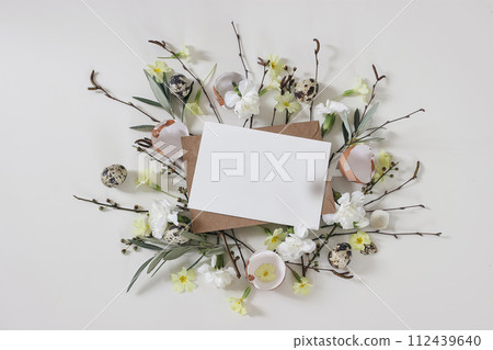 Spring greeting card, Easter invitation mockup. Primrose, white carnation flowers. Birch, olive tree branches, willow catkins twigs. Quail, hen eggs isolated on white table background. Floral flat lay Spring greeting card, Easter invitation mockup. Primrose, white carnation flowers. Birch, olive tree branches, willow catkins twigs. Quail, hen eggs isolated on white table background. Floral flat lay 112439640