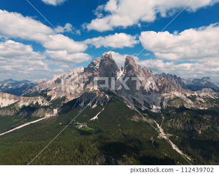 Stunning view of a tourist on the top of a hill enjoying the view of the Cadini di Misurina during sunrise. Cadini di Misurina is a group of mountains located in the Dolomites, Italy. 112439702
