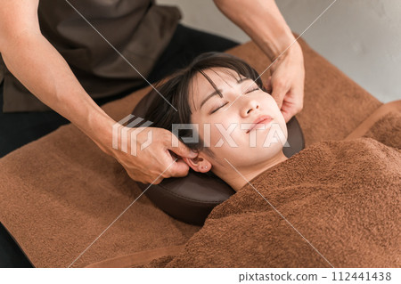 一位女士與針灸師、脊椎按摩師和治療師一起進行耳穴按摩、耳部按摩、壓點推拿和耳穴飲食。 112441438