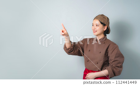 一個穿著烹飪衣服的女人指著 112441449