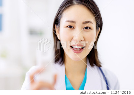 Female doctor checking for fever with a thermometer 112442016