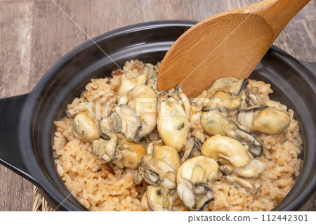 Rice with oysters cooked in an earthenware pot with a rice paddle 112442301