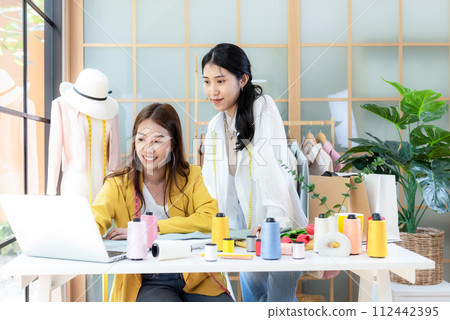 Two young women fashion designer working on her designer in the showroom. Two young women fashion designer working on her designer in the showroom. 112442395