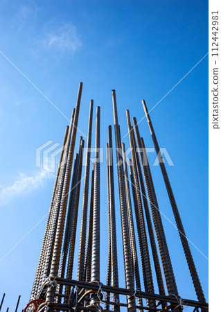 Building construction site A bundle of reinforcing bars stretching into the blue sky b-1 112442981