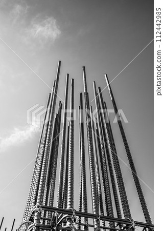 Building construction site A bundle of reinforcing bars stretching against the blue sky b-5 Monochrome 112442985