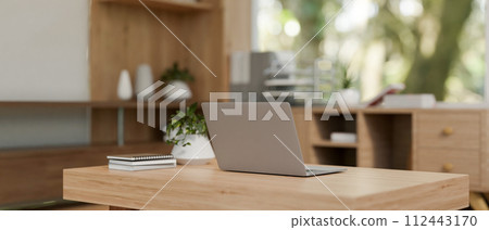 A back view image of a laptop on a wooden coffee table in a cosy Scandinavian home living room. A back view image of a laptop on a wooden coffee table in a cosy Scandinavian home living room. 112443170