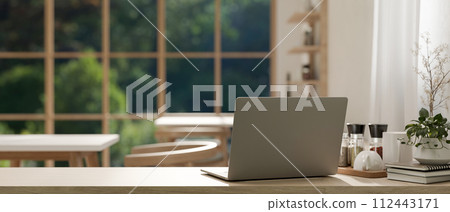 A back view image of a laptop on a wooden table in a cosy Scandinavian coffee shop co-working space A back view image of a laptop on a wooden table in a cosy Scandinavian coffee shop co-working space 112443171