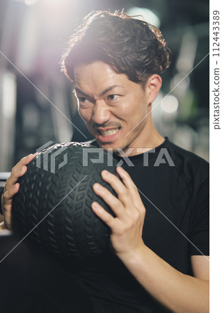 Stoic young man doing sit-ups with a serious expression at the training gym Stoic young man doing sit-ups with a serious expression at the training gym 112443389