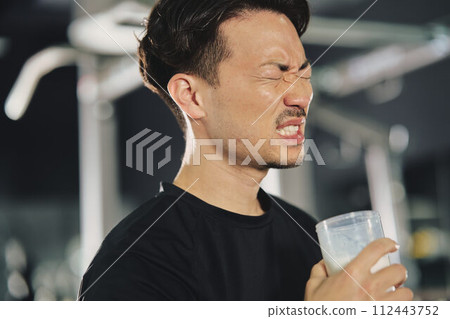 Young man drinking protein at training gym 112443752