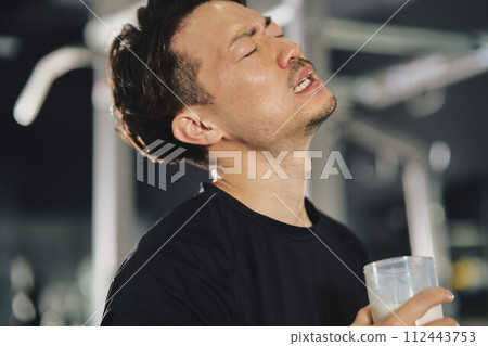 Young man drinking protein at training gym Young man drinking protein at training gym 112443753