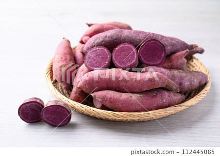 Organic raw sweet potatoes in basket on white table 112445085