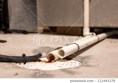 Selective focus on a residential house basement floor drain with furnace and water softener drain lines 112445276