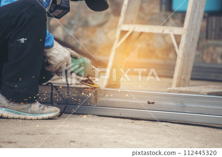 Construction Worker hands using Welding machinery iron metal sparking. Men hands wear protective glove Hot flame metal work cutting fire iron workshop. Locksmith use Welding machine cut metal process 112445320