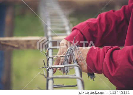 Construction Worker hands using pincer pliers iron wire. Outdoor Worker using wire bending pliers, construction work. Men hands bending cutting steel wire fences bar reinforcement of concrete work 112445321