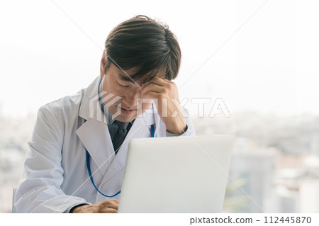 在電腦前憂慮、思考、困擾的男醫生（眼睛疲勞、過勞、疲勞、工作繁忙） 112445870