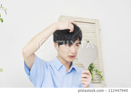 年輕人照鏡子，擔心自己的頭髮 112447940