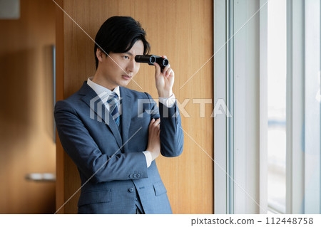 Businessman looking at the building below with binoculars 112448758