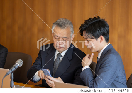 Senior businessman using smartphone during meeting Senior businessman using smartphone during meeting 112449256