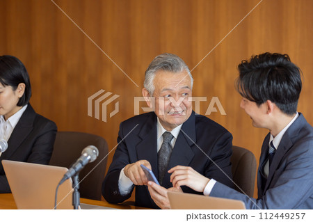 Senior businessman using smartphone during meeting Senior businessman using smartphone during meeting 112449257