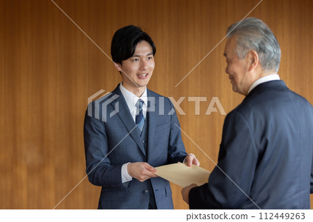 Businessman handing over a confidential envelope 112449263