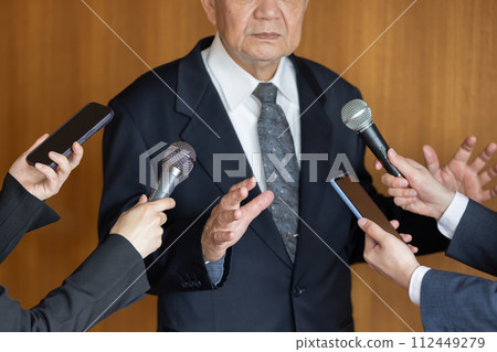 Senior businessman responding to questions from reporters 112449279