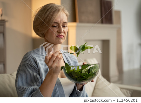 Woman Expresses Discontent While Eating Tasteless Salad at Home 112450201