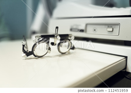 specialised ophthalmologist's spectacles to check vision during an optometric examination of person 112451959