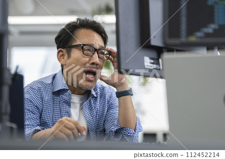 一名 50 多歲的男子看著電腦顯示器,感到很驚訝。 一名 50 多歲的男子看著電腦顯示器,感到很驚訝。 112452214