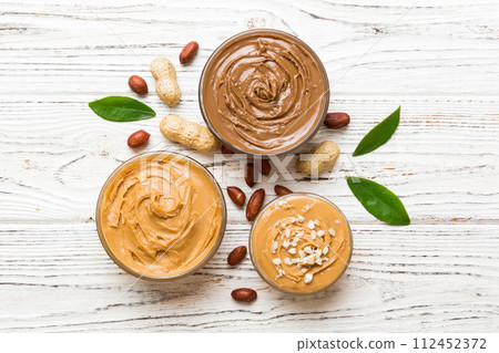 Glass jar with peanut butter on table background, top view space for text and close up 112452372