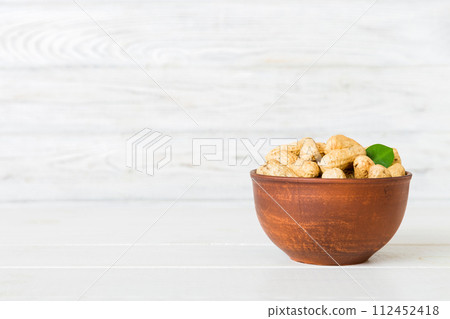Fresh healthy peanuts in bowl on colored table background. Top view Healthy eating bertholletia concept. Super foods Fresh healthy peanuts in bowl on colored table background. Top view Healthy eating bertholletia concept. Super foods 112452418