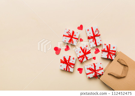 Gift boxes pop out from paper bag top view on colored background. bag packing handmade boxes fall out Concept of holidays, shopping, sale, discounts. Top view, flat lay Gift boxes pop out from paper bag top view on colored background. bag packing handmade boxes fall out Concept of holidays, shopping, sale, discounts. Top view, flat lay 112452475