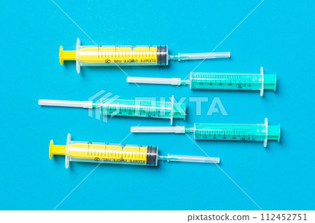 Top view of medical syringes with needles at blue background with copy space. Injection treatment concept Top view of medical syringes with needles at blue background with copy space. Injection treatment concept 112452751