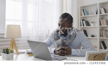 Male office worker having video conference on laptop, listening to business partner talk Male office worker having video conference on laptop, listening to business partner talk 112453368