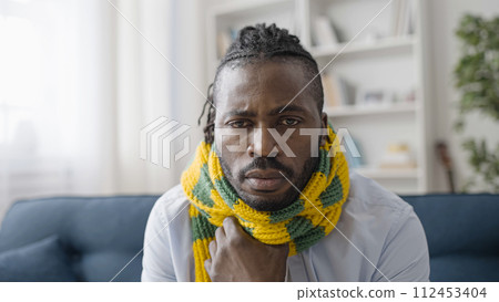 Portrait of upset sick man in warm scarf suffering from flue or cold, coronavirus Portrait of upset sick man in warm scarf suffering from flue or cold, coronavirus 112453404