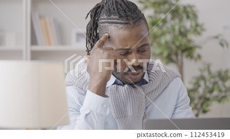 African American male writer thinking of new chapter, working on laptop at home African American male writer thinking of new chapter, working on laptop at home 112453419
