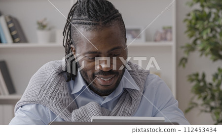African American businessman looking at family photo with a smile during work African American businessman looking at family photo with a smile during work 112453434