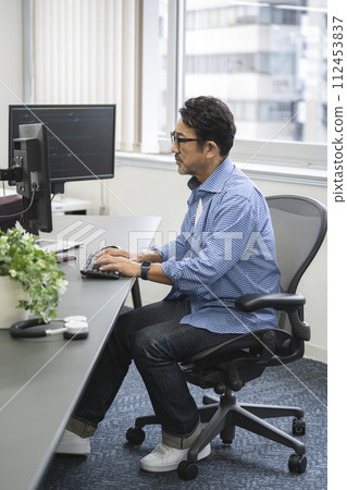 Profile of an engineer in his mid-50s working on a PC 112453837
