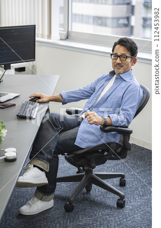 Portrait of a man in his 50s working at a desk looking at the camera 112453982