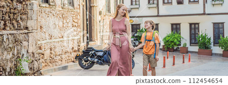BANNER, LONG FORMAT Mom and son tourists in Old town Kaleici in Antalya. Turkiye. Panoramic view of Antalya Old Town port, Taurus mountains and Mediterrranean Sea, Turkey. Traveling with kids concept 112454654