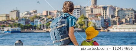 Father and son tourists enjoy Istanbul city skyline in Turkey, Beyoglu district old houses with Galata tower on top, view from the Golden Horn BANNER, LONG FORMAT 112454696