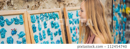 Closeup of beautiful woman looking at Turkish souvenirs for sale in the Grand Bazaar Istanbul, Turkey BANNER, LONG FORMAT Closeup of beautiful woman looking at Turkish souvenirs for sale in the Grand Bazaar Istanbul, Turkey BANNER, LONG FORMAT 112454740