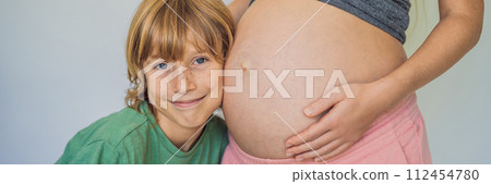 BANNER, LONG FORMAT Young beautiful pregnant woman and eldest son. The cute boy leaned his ear against his mother's belly. Expecting a baby in the family concept. Preparing an older child for a 112454780