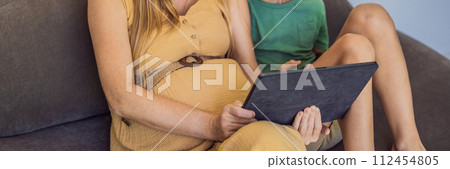 pregnant mom and son look at the tablet. Reading a book or watching a cartoon or making a video call. Look at the photo from the ultrasound BANNER, LONG FORMAT pregnant mom and son look at the tablet. Reading a book or watching a cartoon or making a video call. Look at the photo from the ultrasound BANNER, LONG FORMAT 112454805